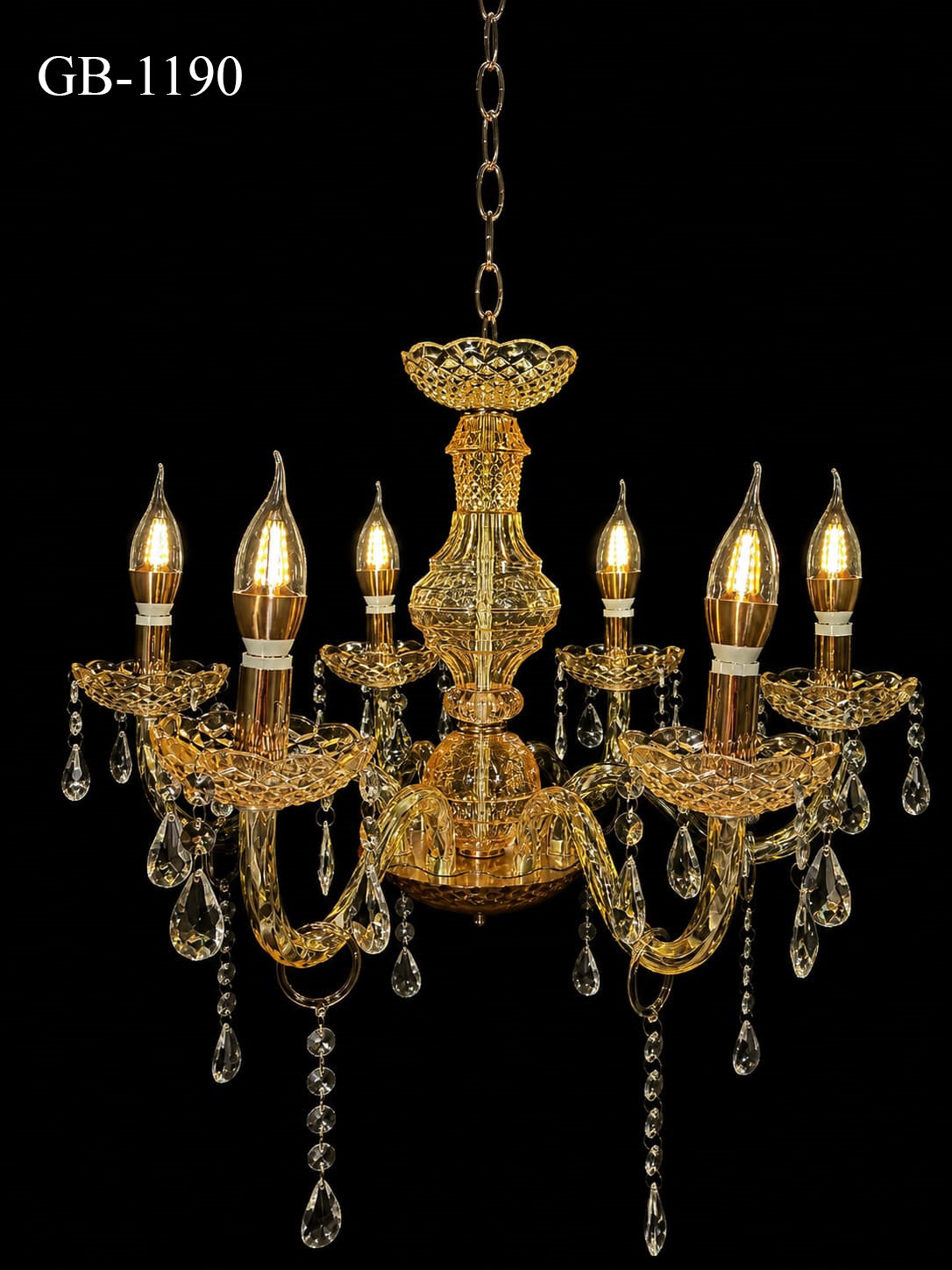An ornate six-light gold chandelier with clear crystal teardrop pendants, shown illuminated